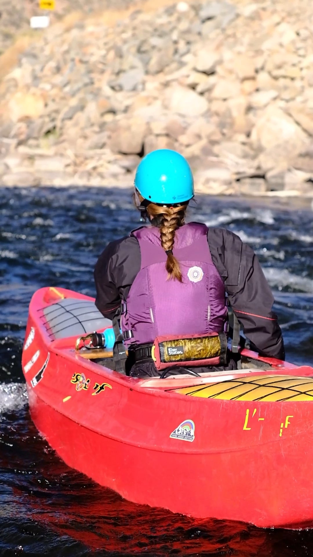 Jodi whitewater canoeing with a purple waist throw bag. 